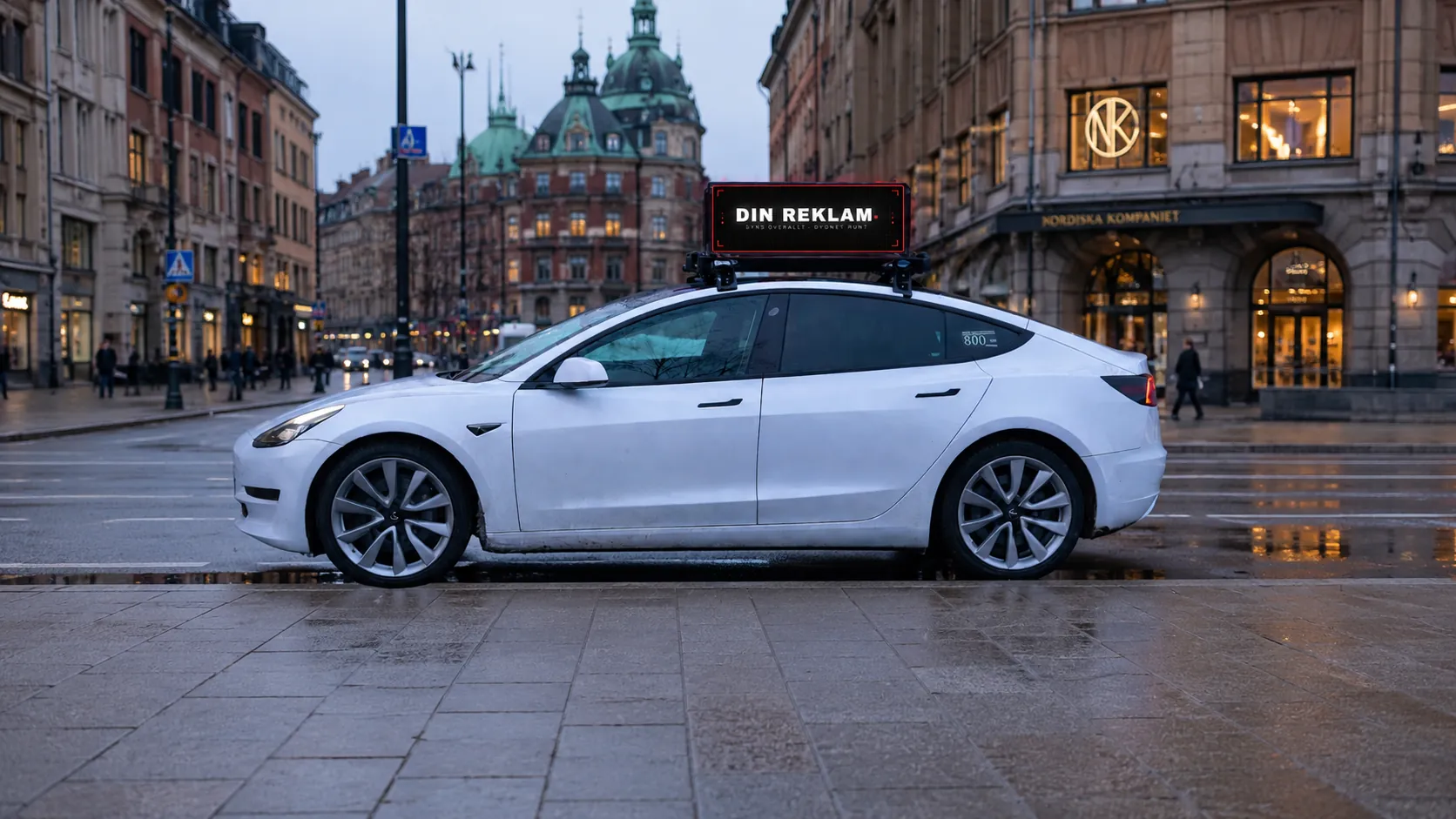 Vit taxi med digital reklamskylt framför NK i Stockholm